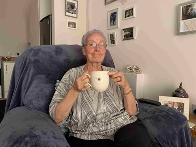 A woman holding a cup of team in a chair in a living room